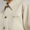 Beige Kinderjacke mit mehrfarbigen Spritzern