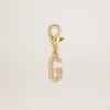 Buchstabe G als Anhänger aus goldfarbenem Messing mit Kristallen