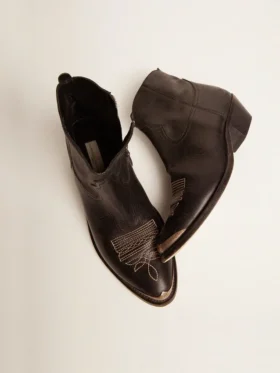 Junge Stiefel aus schwarzem Leder mit sandfarbener Stickerei