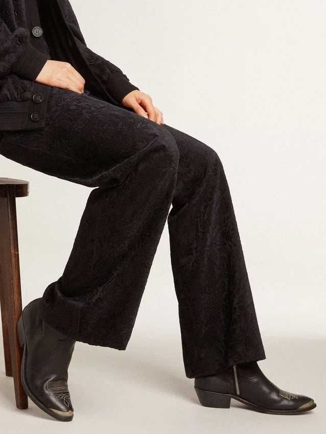 Junge Stiefel aus schwarzem Leder mit sandfarbener Stickerei