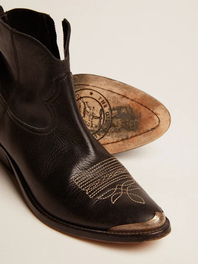 Junge Stiefel aus schwarzem Leder mit sandfarbener Stickerei