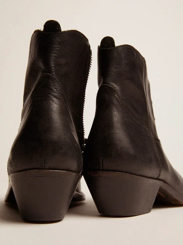 Junge Stiefel aus schwarzem Leder mit sandfarbener Stickerei