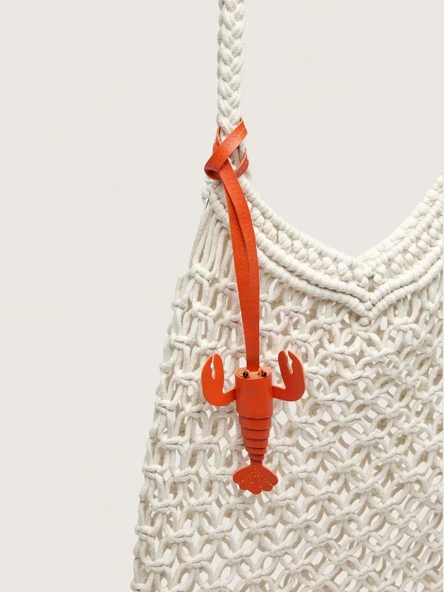 Makramee-Damenhandtasche aus butterfarbener Baumwolle mit einem Lederanhänger in Form einer Hummerklammer