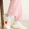 May Young mit fuchsiafarbenem Glitzerstern und Absatzlasche aus Metallic-Leder