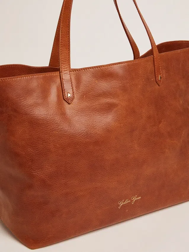 Pasadena-Tasche aus hellbraunem, glänzendem, gehämmertem Leder mit goldenem Logo auf der Vorderseite