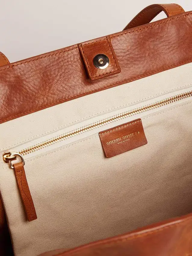 Pasadena-Tasche aus hellbraunem, glänzendem, gehämmertem Leder mit goldenem Logo auf der Vorderseite