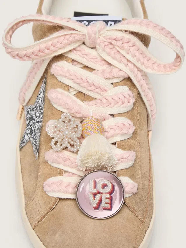 Schnürsenkel aus Lederwaren in Hellbeige mit rosa Zierflechtung, Anstecknadel und Applikationen