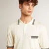 Weiss geträgtes Herren-Strick-Polohemd mit blauen Rippenbündchen