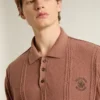 Ziegelrotes Herren-Polo mit gesticktem Logo.